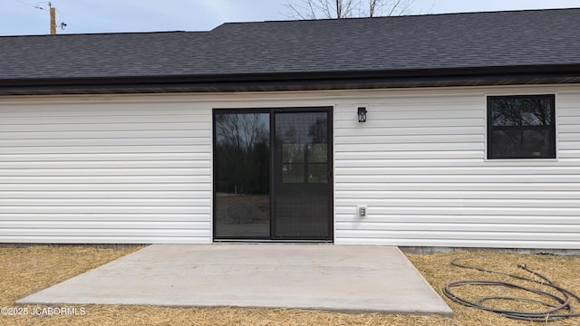 doorway to property with roof with shingles and a patio area