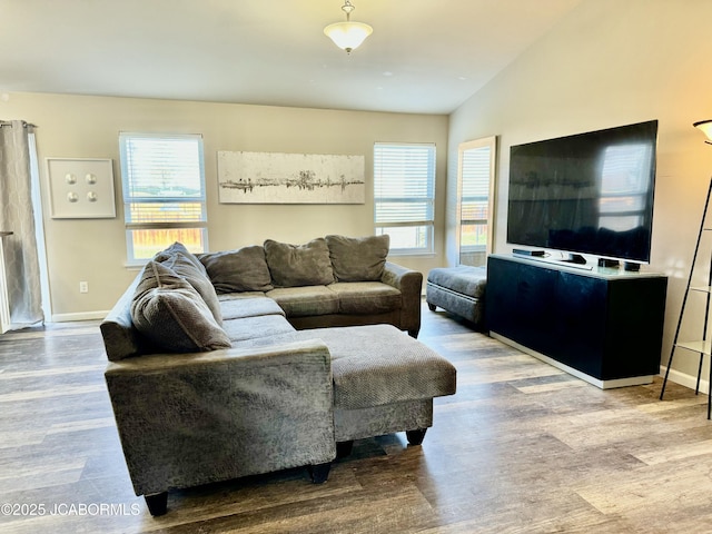 living area featuring baseboards, vaulted ceiling, and wood finished floors