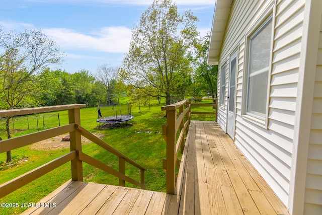 wooden terrace featuring a lawn and a trampoline