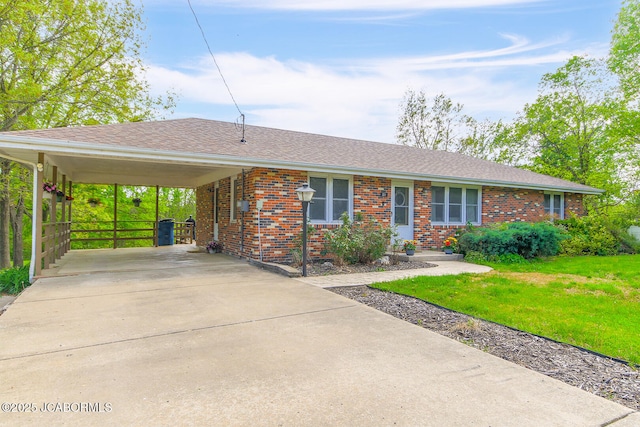 single story home with roof with shingles, a front lawn, brick siding, concrete driveway, and a carport