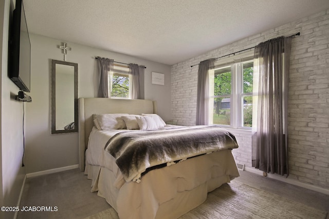bedroom with baseboards, a textured ceiling, brick wall, and light carpet