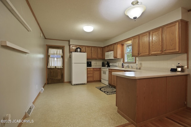 kitchen featuring brown cabinets, white appliances, light countertops, a peninsula, and baseboards