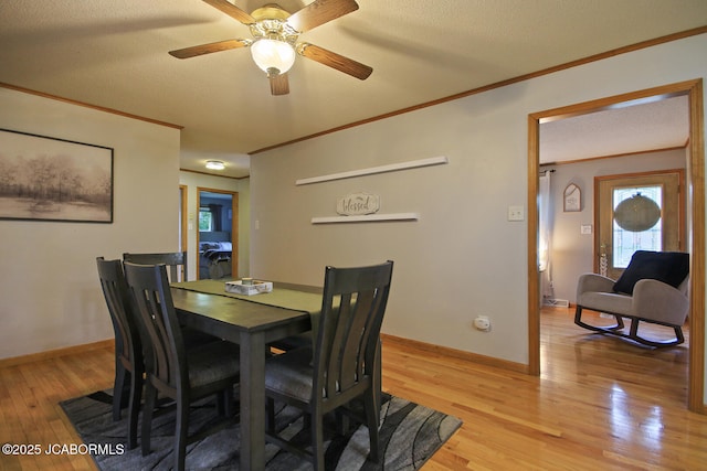 dining space featuring ornamental molding, baseboards, a textured ceiling, a ceiling fan, and light wood finished floors