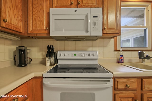 kitchen featuring light countertops, decorative backsplash, and white appliances