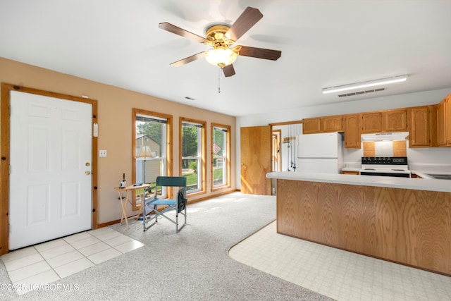 kitchen with electric range oven, light countertops, freestanding refrigerator, under cabinet range hood, and visible vents