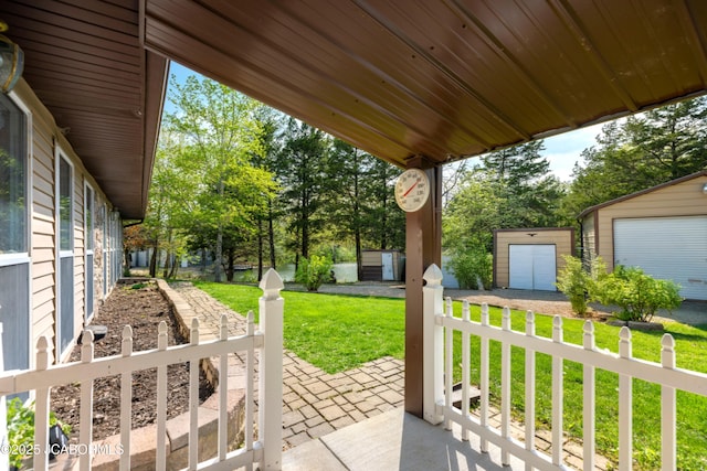 view of patio / terrace with a garage, an outdoor structure, a shed, and dirt driveway