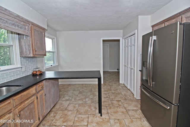 164 Turn Back Now Trl, Linn, MO 65051 - kitchen featuring stainless steel refrigerator with ice dispenser, dark countertops, decorative backsplash, stone finish flooring, and brown cabinets