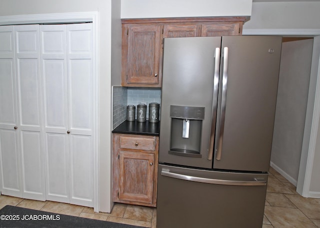 164 Turn Back Now Trl, Linn, MO 65051 - kitchen featuring stainless steel fridge, light tile patterned floors, dark countertops, tasteful backsplash, and brown cabinetry