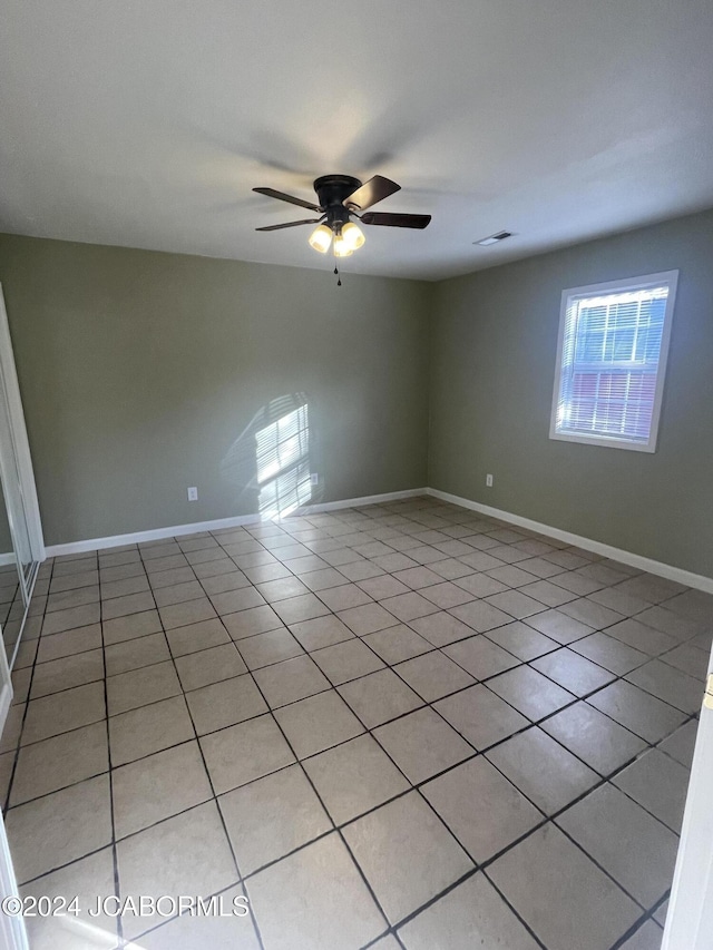 empty room with ceiling fan and light tile patterned floors