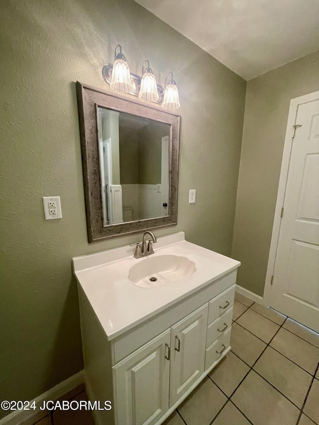 bathroom with toilet, vanity, and tile patterned floors