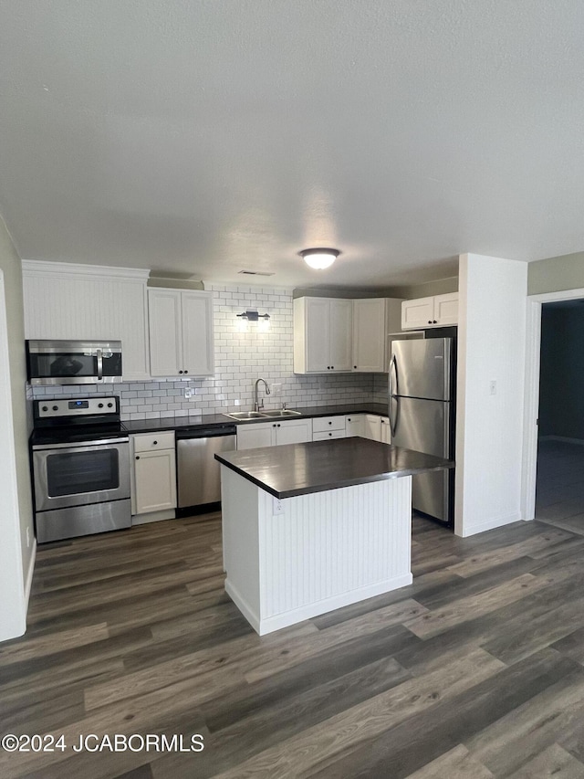 kitchen with white cabinets, sink, decorative backsplash, dark hardwood / wood-style flooring, and stainless steel appliances