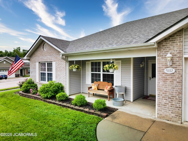 5112 Melissa Dr, Columbia, MO 65202 - property entrance with covered porch, a shingled roof, brick siding, and a lawn