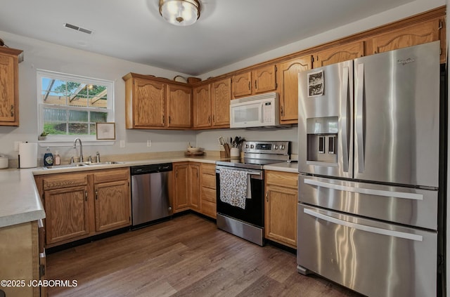 5112 Melissa Dr, Columbia, MO 65202 - kitchen with appliances with stainless steel finishes, dark wood finished floors, light countertops, and brown cabinetry