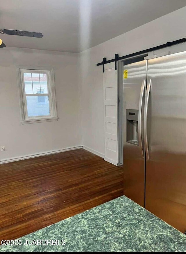 kitchen featuring a barn door, dark wood-type flooring, stainless steel fridge, and ceiling fan