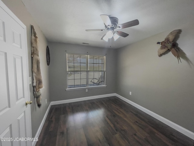 unfurnished room featuring visible vents, baseboards, dark wood-style flooring, and ceiling fan