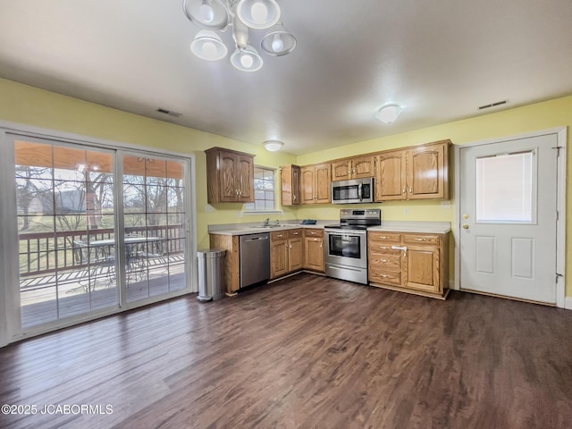 kitchen with dark wood-style floors, visible vents, a sink, stainless steel appliances, and light countertops