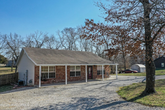 view of front of home featuring brick siding, cooling unit, a porch, and fence