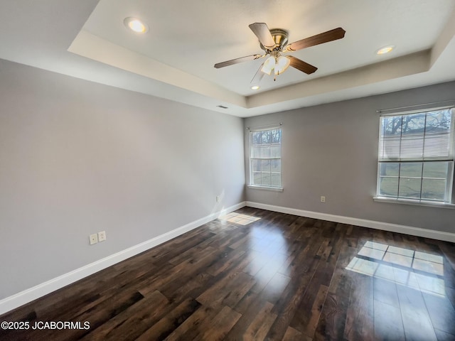 spare room with ceiling fan, baseboards, dark wood finished floors, recessed lighting, and a raised ceiling