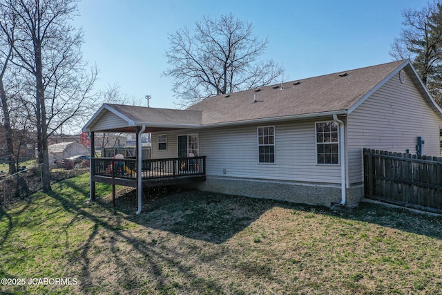 back of house with a wooden deck, a lawn, roof with shingles, and fence