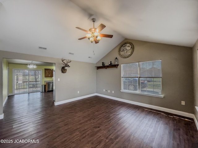 unfurnished living room with visible vents, ceiling fan with notable chandelier, dark wood finished floors, baseboards, and lofted ceiling