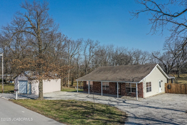 view of front of home with brick siding, a detached garage, an outdoor structure, and fence