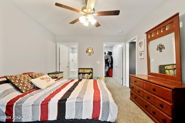 carpeted bedroom featuring a ceiling fan and ensuite bath