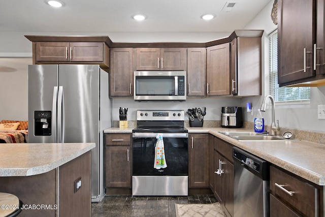 kitchen featuring stainless steel appliances, light countertops, visible vents, a sink, and dark brown cabinetry