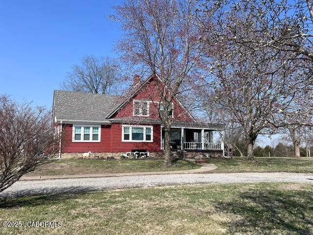 view of front of home featuring a porch, a front lawn, and a chimney