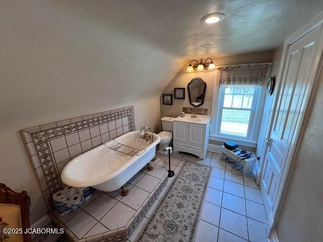 full bathroom featuring vanity, lofted ceiling, a freestanding tub, and tile patterned flooring