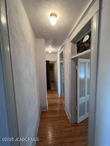 corridor featuring wood finished floors and baseboards