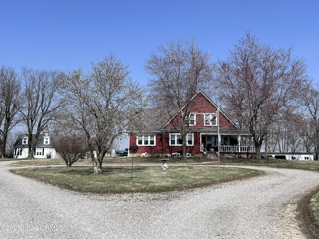 view of front of home with driveway, covered porch, and a front yard
