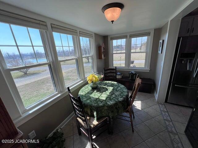 tiled dining space featuring plenty of natural light and baseboards