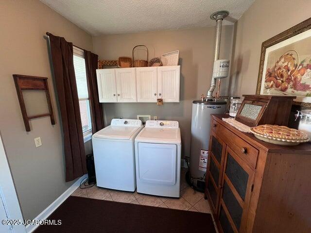 washroom with gas water heater, washer and dryer, light tile patterned floors, cabinet space, and a textured ceiling