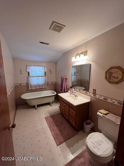 bathroom featuring a bathtub, vanity, vaulted ceiling, and toilet