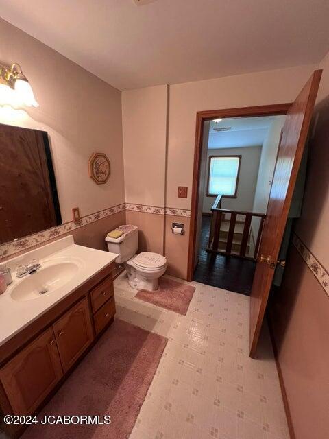 bathroom with vanity, tile walls, and toilet