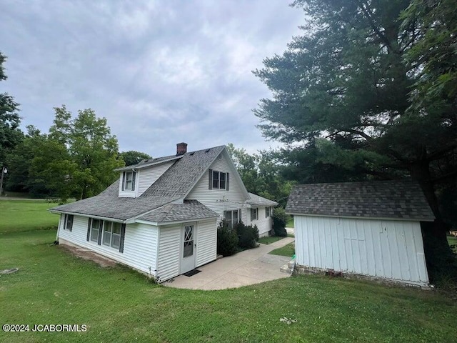 rear view of property featuring a storage unit, a patio area, and a lawn