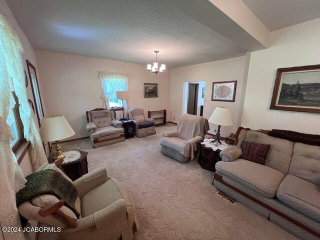 living room with carpet flooring, a textured ceiling, and an inviting chandelier