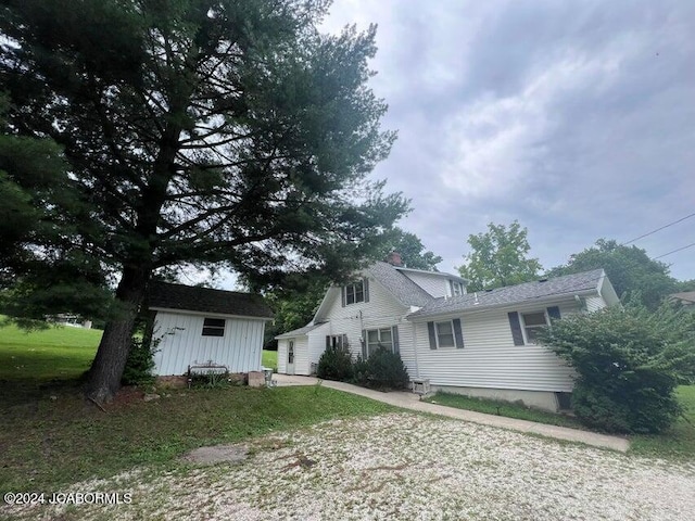 back of property with a lawn and an outdoor structure