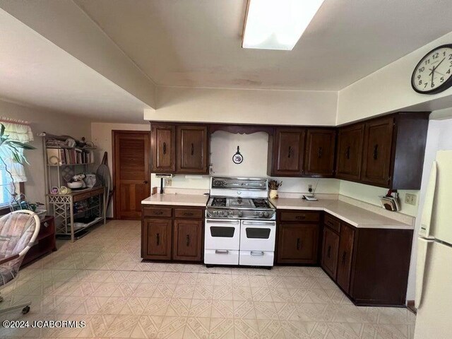 kitchen featuring dark brown cabinetry and white appliances