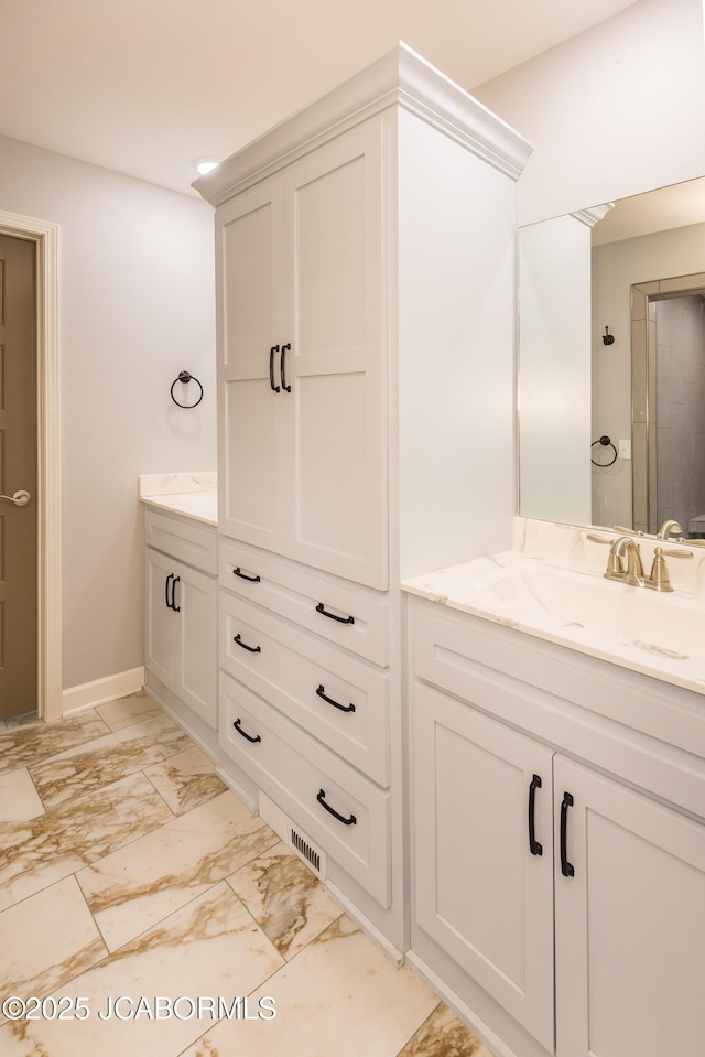 full bath featuring marble finish floor, vanity, and baseboards