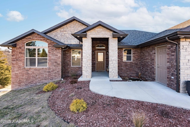 view of front of property with a shingled roof and brick siding