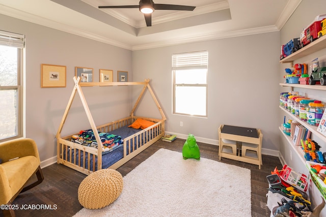 bedroom with ornamental molding, a tray ceiling, wood finished floors, and baseboards