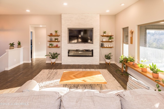 living area featuring a large fireplace, recessed lighting, wood finished floors, and baseboards