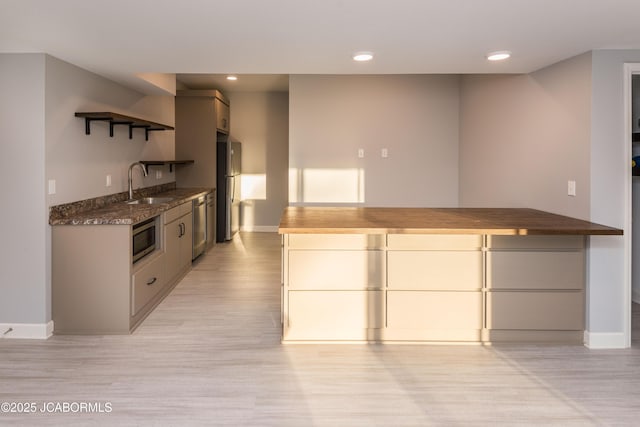 kitchen with stainless steel appliances, open shelves, light wood-type flooring, and a sink