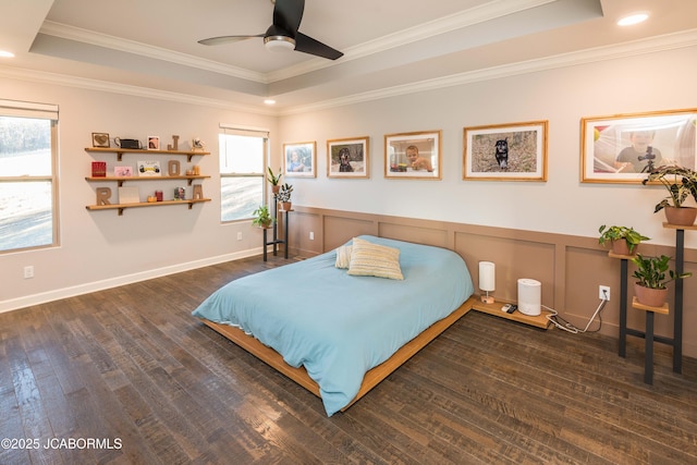 bedroom with a wainscoted wall, crown molding, a raised ceiling, a decorative wall, and hardwood / wood-style floors