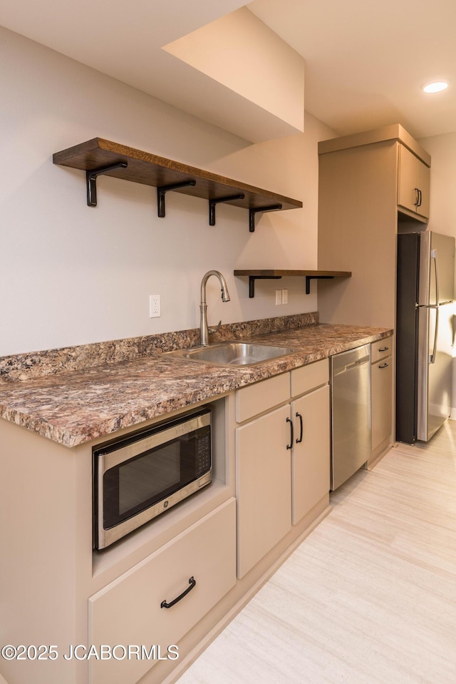 kitchen with a sink, stainless steel appliances, open shelves, and light wood-style flooring