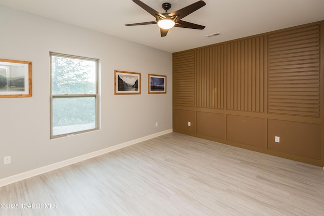 empty room featuring light wood finished floors, visible vents, baseboards, and a ceiling fan