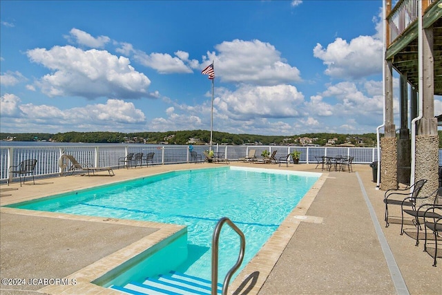 view of swimming pool with a water view and a patio