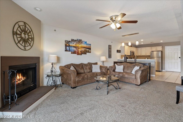 carpeted living room featuring ceiling fan and a textured ceiling