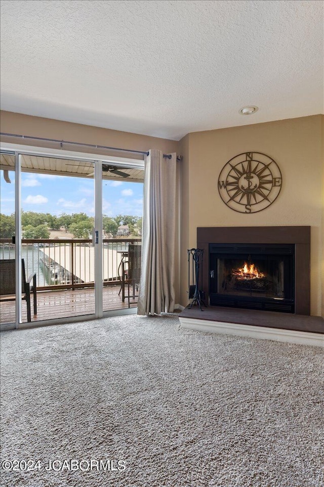 unfurnished living room featuring carpet flooring, a textured ceiling, and a water view